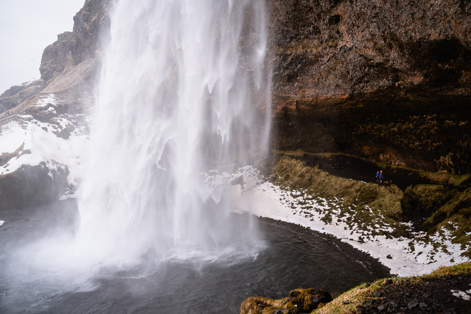 Twee kinderen staan achter de Seljalandsfoss waterval in IJsland