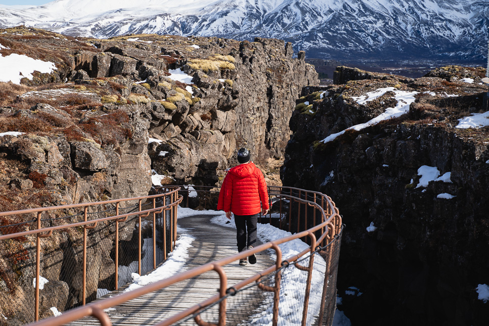 Man wandelt tussen de Noord-Amerikaanse en Euraziatische tectonische platen in Thingvellir Nationaal Park in IJsland