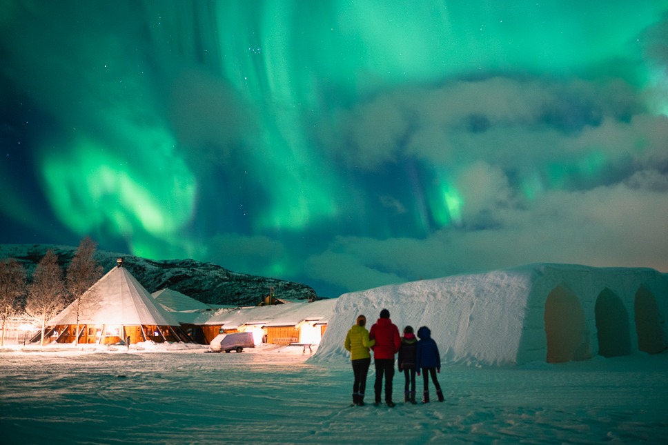 Gezin kijkt naar het noorderlicht in de sneeuw in Alta in Noorwegen