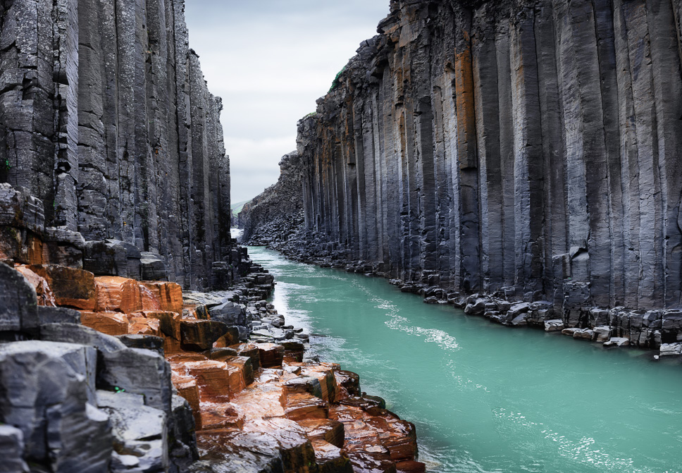 Stuðlagil Canyon met de grijze basalt kolommen en de turquoise rivier die erdoor stroomt