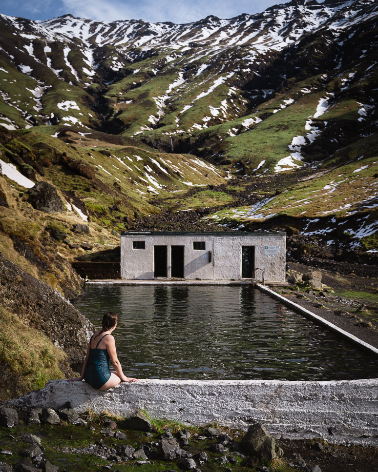 Vrouw op de rand van Seljavallalaug Pool aan de zuidkust van Ijsland
