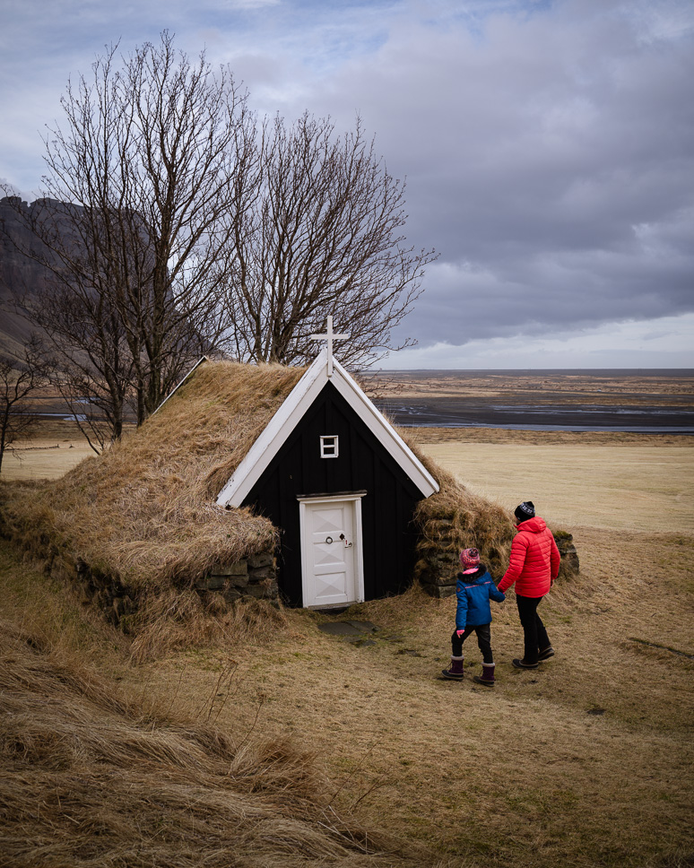 Papa en kind wandelen naar het onbekende turfkerkje Núpsstaðakirkja in Zuid Ijsland