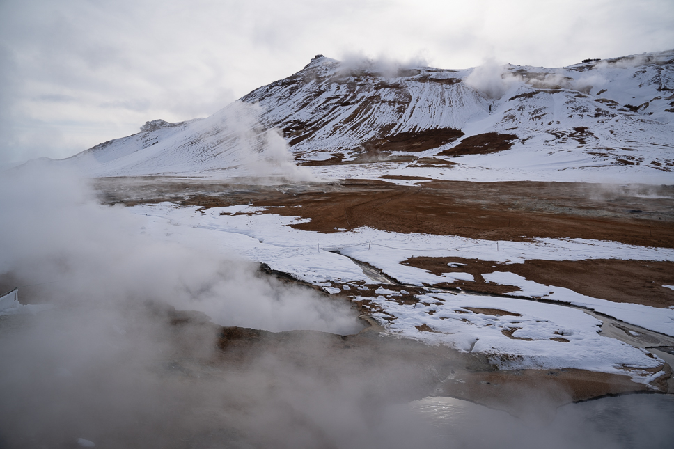 Thermische activiteit en stomende  modderpoelen tussen besneeuwde bergen in Hverir bij Myvatn in Noord-IJsland