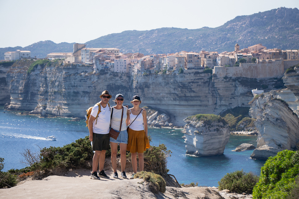 Family on the cliffside trail with the citadel of Bonifacio in the background.
